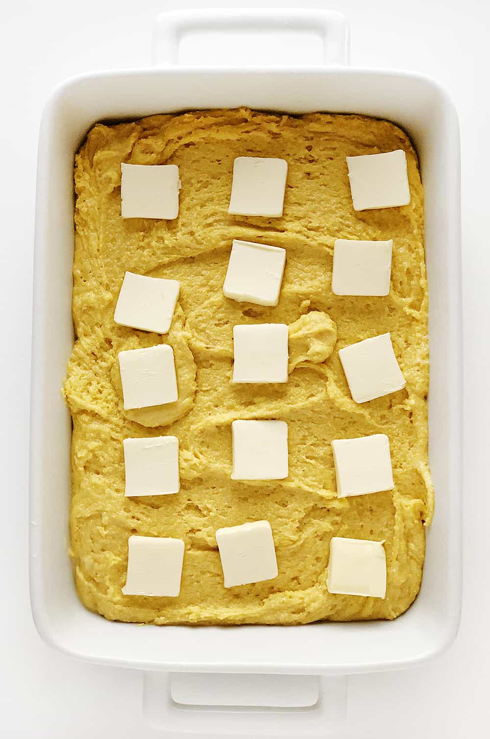一盘未烤的甜玉米面包，上面涂有黄油