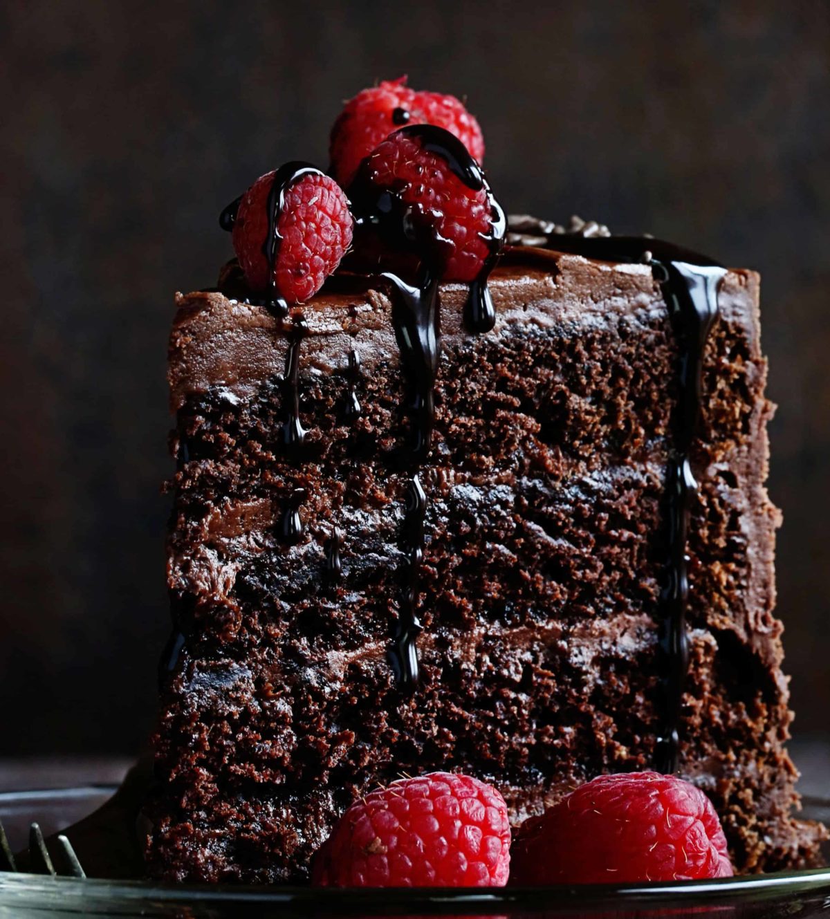 一块巧克力蛋糕放在盘子里，上面放着覆盆子
