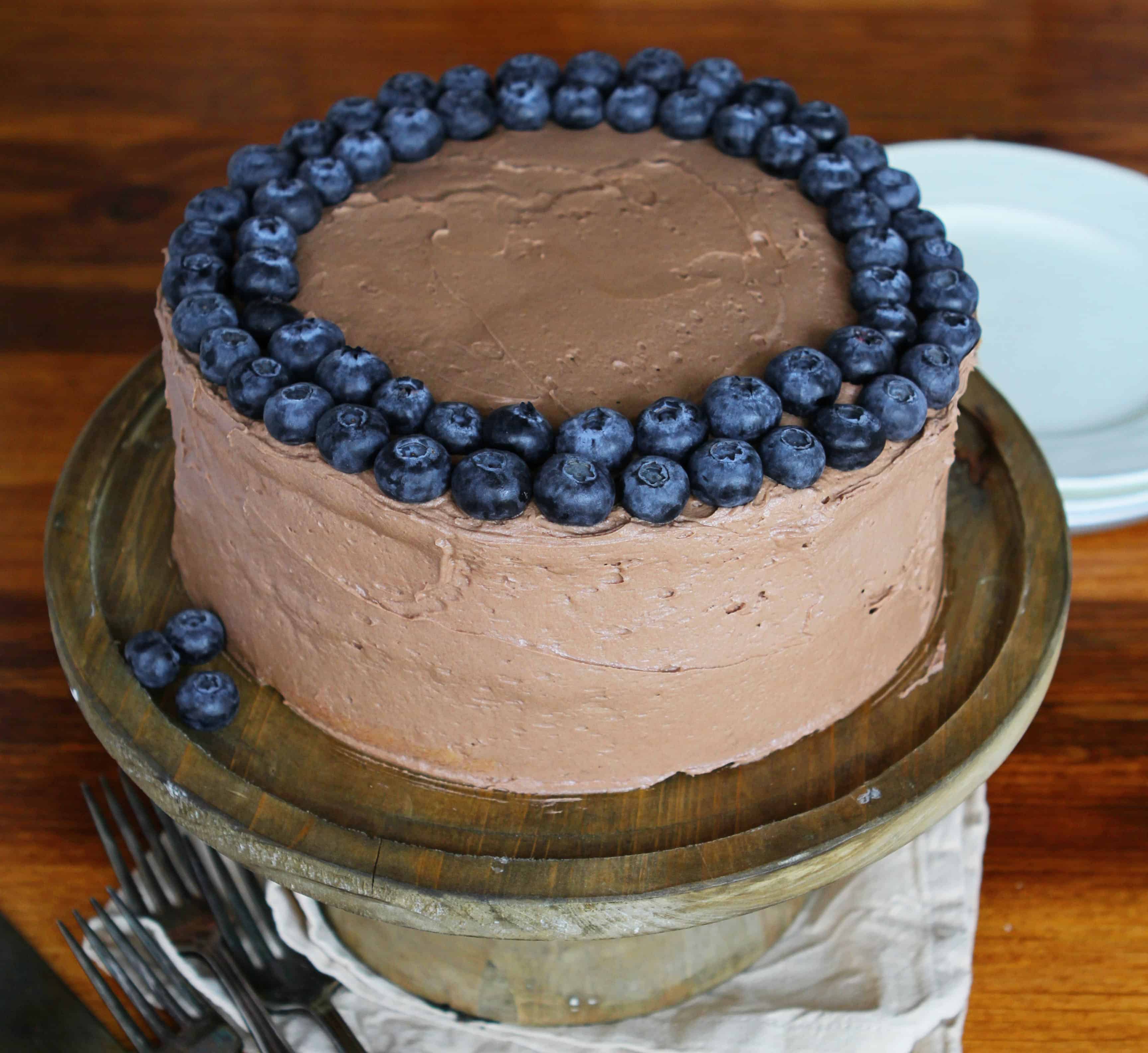 与夏南瓜的白蛋糕用巧克力结霜和蓝莓在木桌上与板材在背景中