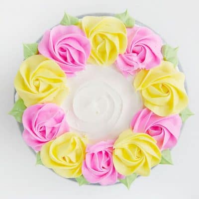 在Buttercream中创建简单的仿古线，然后用粉红色和黄色奶油玫瑰花饰有菠萝！
