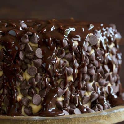 在一个质朴的木制蛋糕架上，覆盖着一层巧克力蛋糕，上面淋上巧克力糖浆。