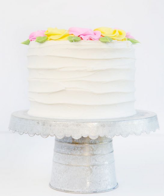 在将简单的粉红色和黄色玫瑰花到顶部添加简单的粉红色和黄色玫瑰花时，在这个蛋糕两侧创造仿古线。