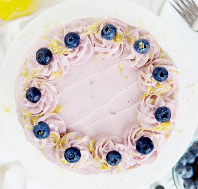 俯视一个覆盖着蓝莓奶油、蓝莓和柠檬皮的柠檬蛋糕。