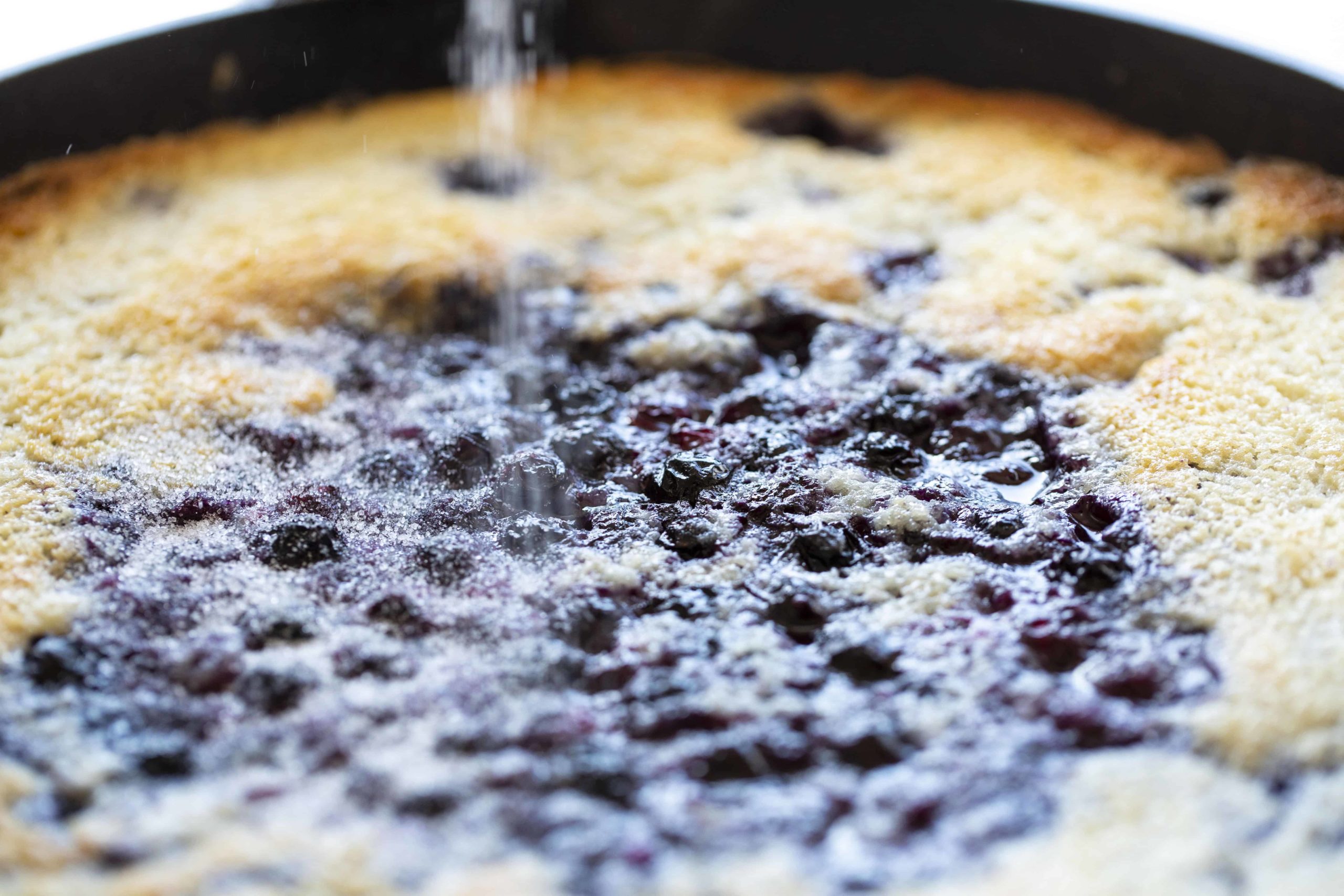 在平底锅里，在蓝莓馅饼上撒上糖