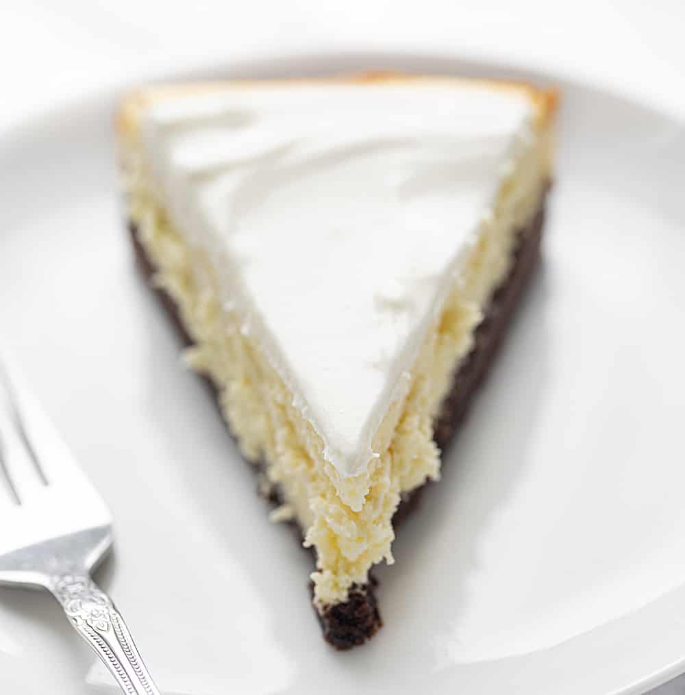 一块Brownie Bottom芝士蛋糕放在白色盘子里，旁边放着叉子