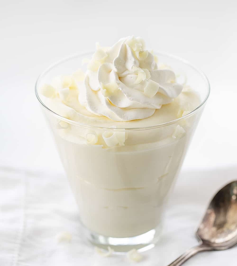 在一个低级球玻璃的两种成分白色巧克力奶油甜点与打好的奶油