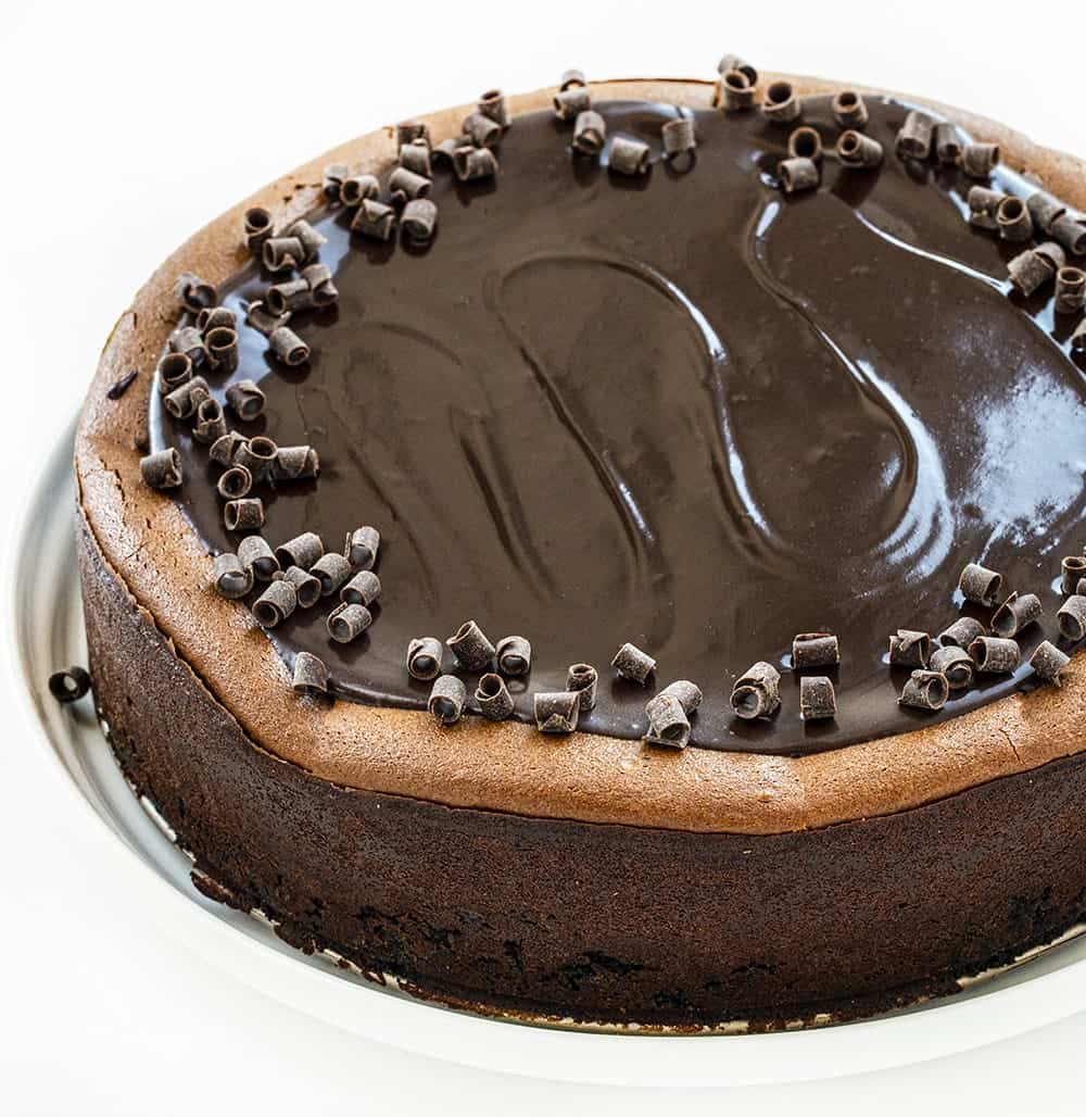 头顶上的三层巧克力芝士蛋糕展示了闪亮的顶部和巧克力卷