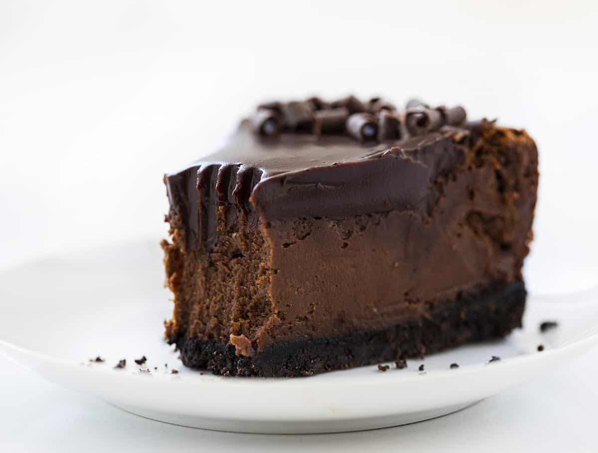 一块巧克力芝士蛋糕，在一个白色盘子上，从顶端去掉咬口