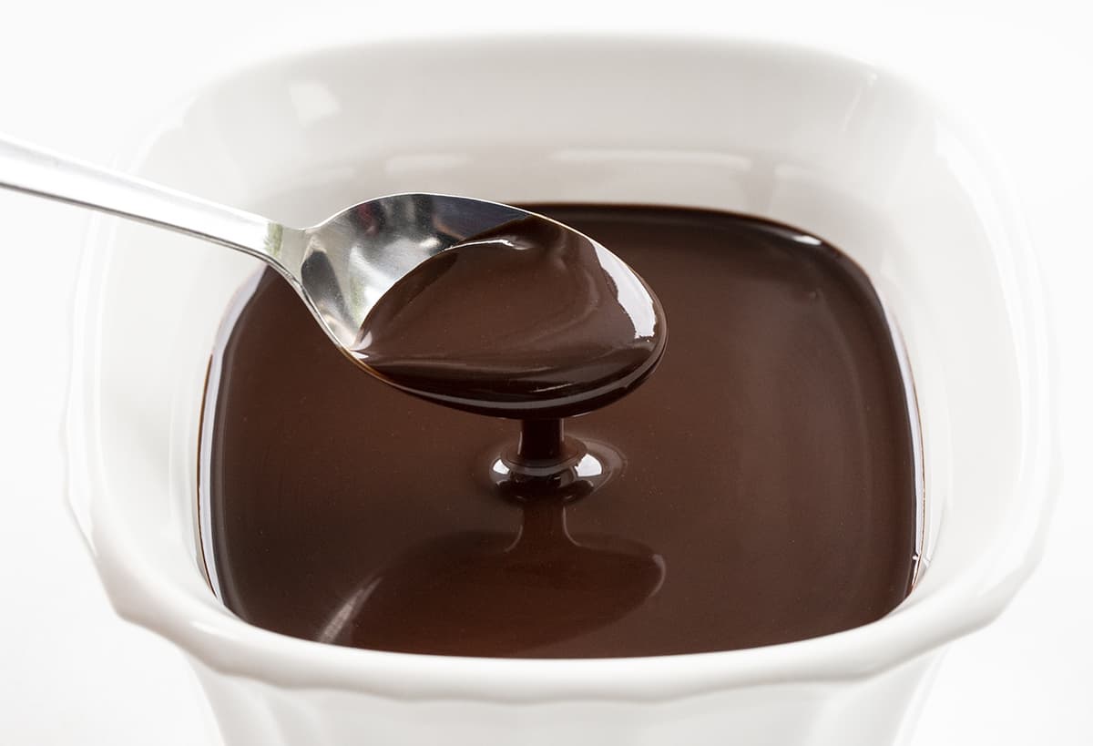 在白色方形容器中的一勺自制巧克力乳脂软糖酱