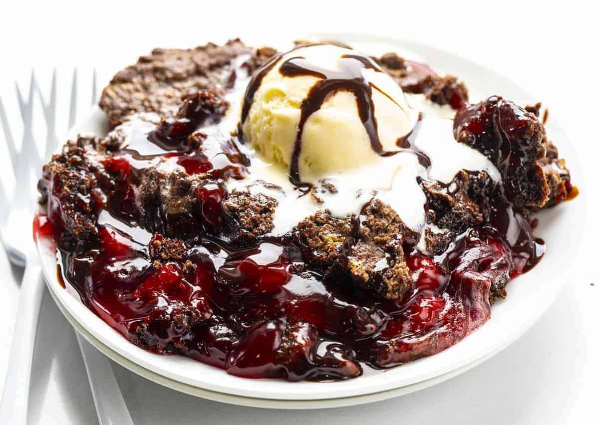 一盘巧克力樱桃蛋糕配冰淇淋和两把白色叉子
