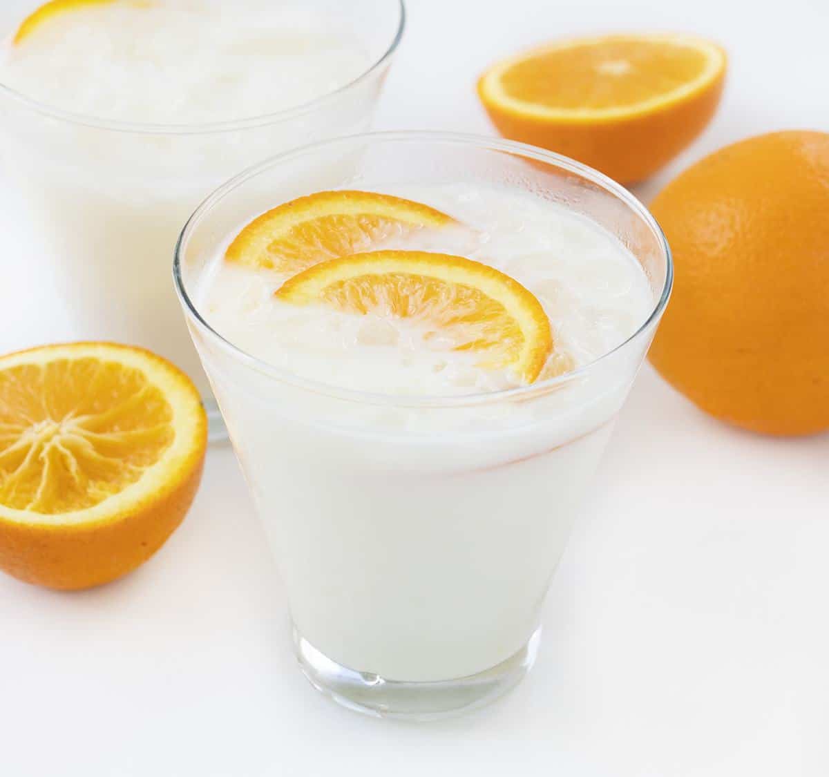 在鸡尾酒玻璃的冰纹橙色乳膏饮料用周围的桔子